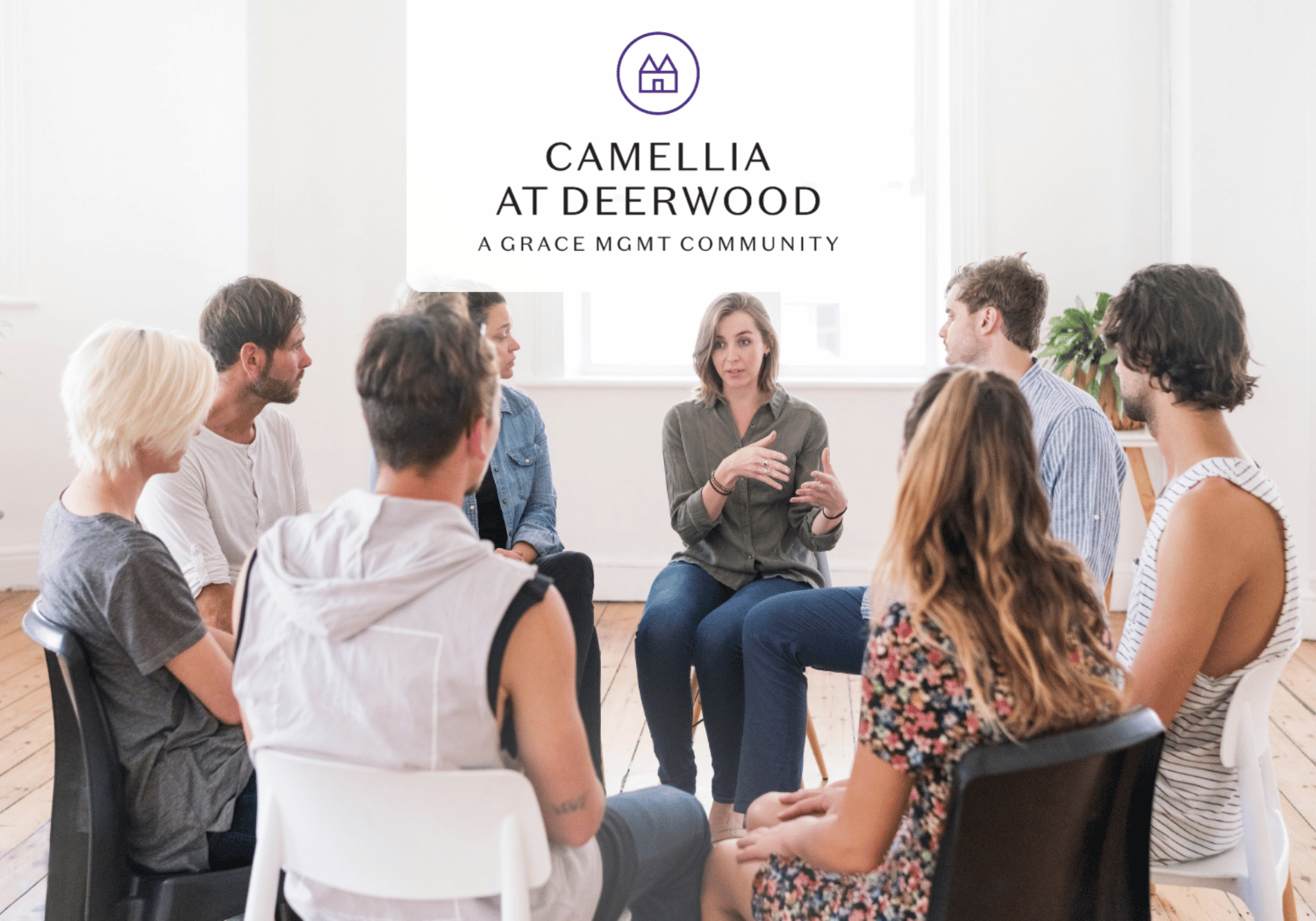 Group of adults seated in a circle in a bright room, discussing; logo reading 'Camellia at Deerwood' above.